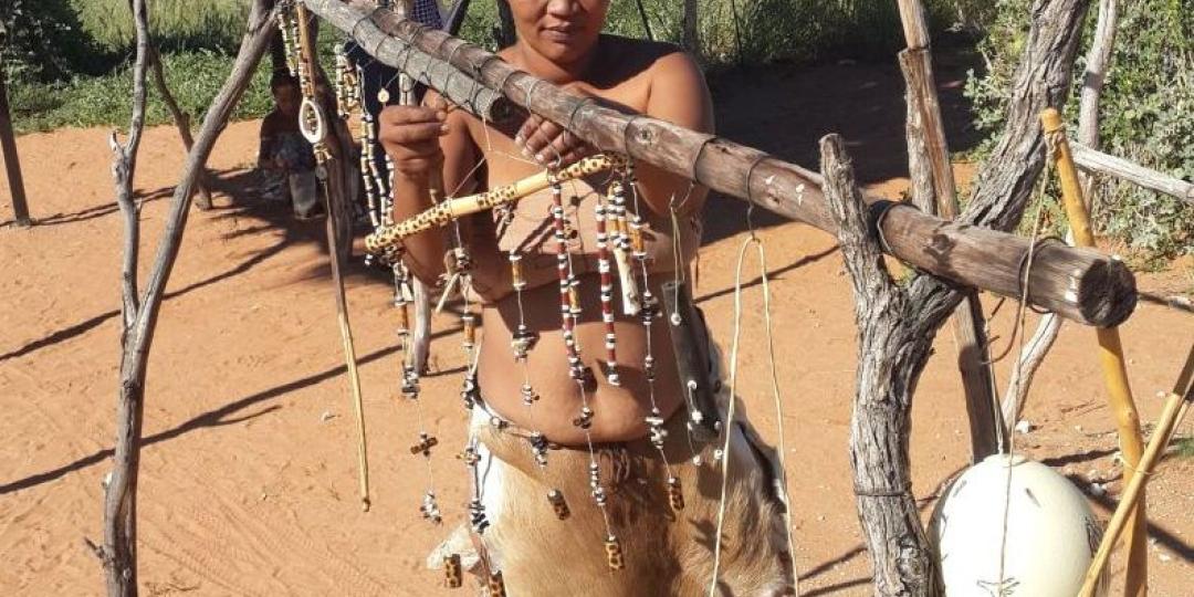 Khomani San woman creating beadwork using local materials. 